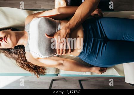 Frau, die sich auf einer Bahre zur viszeralen Manipulation in einer medizinischen Klinik niederlegt Stockfoto