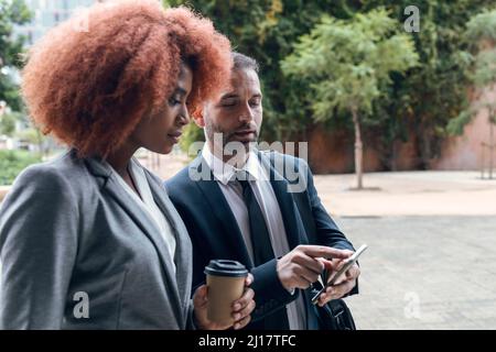 Geschäftsmann zeigt einer Kollegin etwas auf dem Smartphone Stockfoto