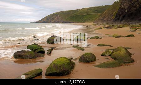 Farbfoto der Küstenfelsen am Strand einige geglättet und abgerundet durch die Passagen von Zeit und Flut mit Steinkobbeln und Kieselsteinen, die auf t liegen Stockfoto
