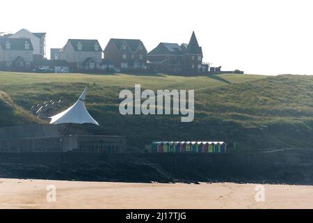 Häuser und Strandhütten am Nell's Point überblicken den einsamen Sandstrand von Whitmore Bay, Barry Island, an einem sonnigen Tag am frühen Morgen. Stockfoto