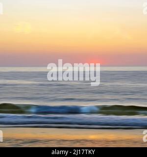 Farbfoto der Sommersonne am Horizont der irischen See, aufgenommen an der Küste von Penbryn in der Cardigan Bay im Südwesten von Wales Stockfoto