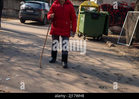 Kiew, Maine, Ukraine. 23. März 2022. Eine ältere Frau geht über Beton, der von einem Granatsplitter aus einer russischen Muschel in Kiew beschädigt wurde. (Bild: © Seth Sidney Berry/ZUMA Press Wire) Bild: ZUMA Press, Inc./Alamy Live News Stockfoto