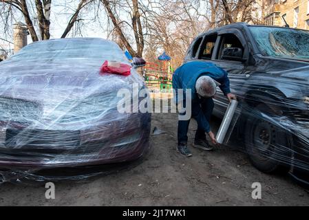 Kiew, Maine, Ukraine. 23. März 2022. Ein Bewohner umhüllte sein Auto mit Plastik, um Schäden durch Schrapnel in Kiew zu vermeiden. (Bild: © Seth Sidney Berry/ZUMA Press Wire) Bild: ZUMA Press, Inc./Alamy Live News Stockfoto