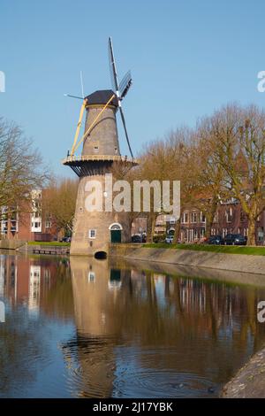 Eine Windmühle in schiedam in Holland mit einem Fluss davor Stockfoto