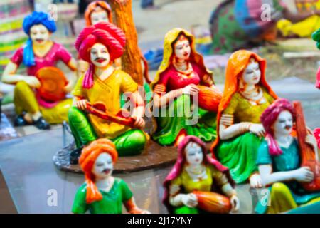 Verschwommenes Bild von bunten männlichen und weiblichen Terrakotta-Puppen in traditionellen indischen Kleidern, Musikinstrumente spielend, hergestellt in Krishnanagar, N Stockfoto