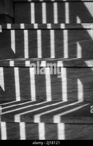 Eine Graustufenaufnahme von Fensterschatten auf einer Treppe Stockfoto