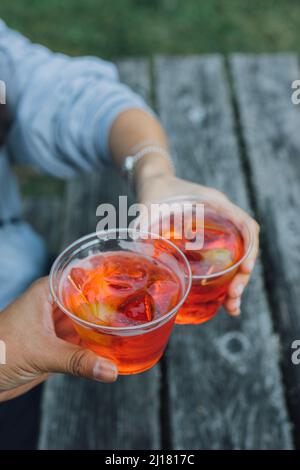 Prost mit zwei aperol Spritz Cocktails in Plastikbechern Stockfoto