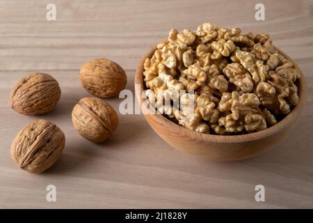 Schale aus Walnüssen und ganzen Walnusskernen auf Holzhintergrund, Draufsicht Stockfoto