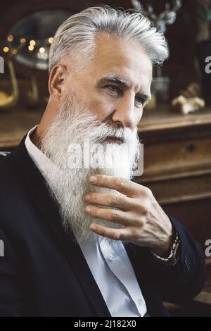 Gutaussehender bärtiger älterer Mann, der im Studio posiert Stockfoto