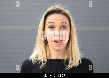 Kopf- und Schulterporträt einer hübschen jungen blonden Frau mit ausgestreckter Zunge Stockfoto