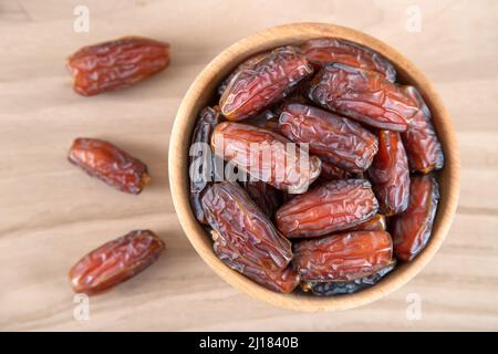 Dattobst in Schale auf Holzhintergrund, Draufsicht Stockfoto