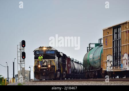 BENSENVILLE, Illinois, USA. Ein Arbeiter fährt vorne, vor einer Lokomotive der Norfolk Southern Railway, die einen Güterzug der Canadian Pacific Railway hinführt Stockfoto