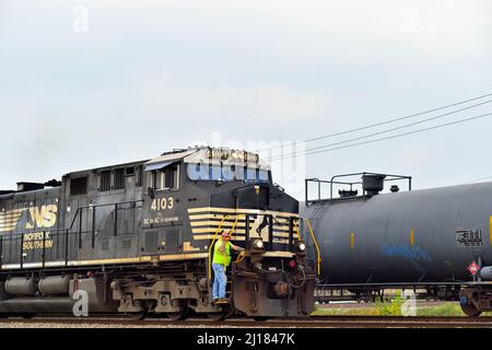 BENSENVILLE, Illinois, USA. Ein Arbeiter fährt auf den Stufen einer Lokomotive der Norfolk Southern Railway, die einen Güterzug der Canadian Pacific Railway führt. Stockfoto