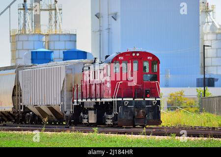 Rochelle, Illinois, USA. Eine Burlington Junction Railway Lokomotive umstellt Autos in einem Industriegebiet von Rochelle, Illinois. Stockfoto