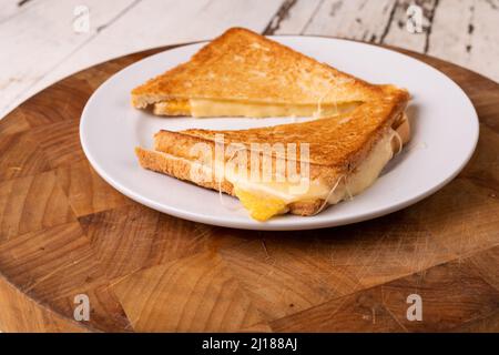 Nahaufnahme des frischen Käsesandwiches, das auf einem Teller auf einem Holzbrett serviert wird Stockfoto