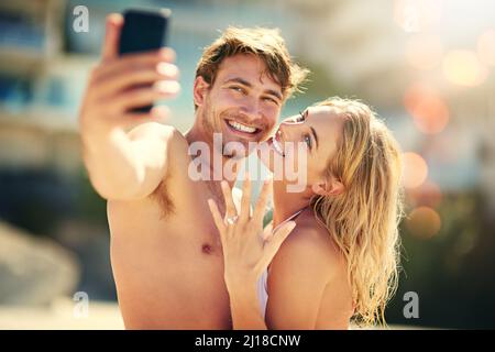 Liebe meinen Ehering. Ausgeschnittene Aufnahme einer jungen Frau, die ihren Ehering zeigt, während sie ein Selfie mit ihrem Mann machte. Stockfoto
