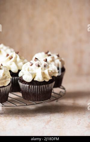 Reichhaltige Schokoladen-Cupcakes mit Schlagsahne und Schokoladenstückchen. Stockfoto