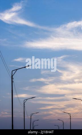 Zwei Reihen Straßenlaternen am Abend unter dem dramatischen blauen Himmel mit Kopierraum Stockfoto