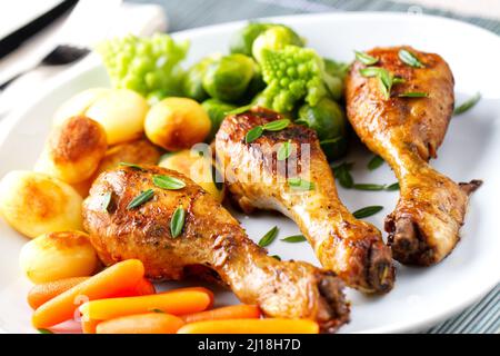 Hühnerschenkel mit Kartoffeln, Karotten, Broccoli und Rosenkohl braten Stockfoto