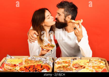 Liebevolles Paar, das Pizza isst und küsst. Liebeskonzept. Glückliche Familie zu Hause zu Abend essen. Fast Food Stockfoto