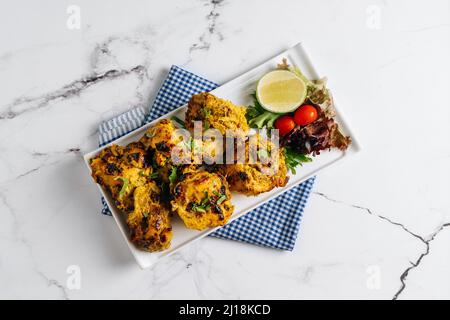 Kali Mirchi oder Schwarzer Pfeffer Rindfleisch Kebab mit Limette in einem Gericht isoliert auf Serviette Seitenansicht auf grauem Hintergrund Stockfoto