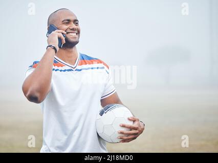 Ich bin so glücklich, deine Stimme zu hören. Aufnahme eines jungen Fußballspielers, der einen Anruf tätigen und dabei einen Fußball halten soll. Stockfoto