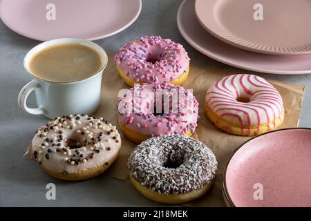 Mehrere Donuts liegen auf handgezogenem Pergamentpapier auf grauer Oberfläche Stockfoto