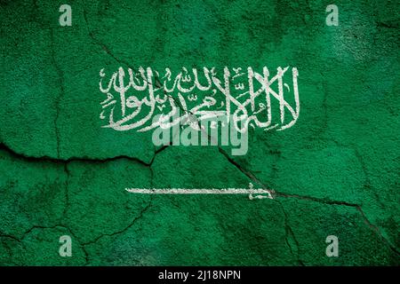 Vollformatfoto einer verwitterten Flagge Saudi-Arabiens, gemalt auf einer rissigen Wand. Stockfoto