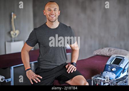 Die Gesundheit der Kunden ist meine einzige Sorge. Aufnahme eines Trainers, der in einem Fitnessstudio an Geräten sitzt. Stockfoto