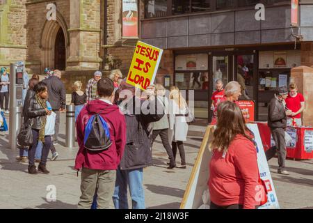 Ein Straßenprediger hält ein Schild hoch, das sagt, Jesus sei der Herr in einem geschäftigen Einkaufsviertel im Stadtzentrum. Stockfoto