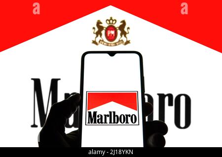 In dieser Abbildung ist ein Marlboro-Logo auf einem Smartphone mit einem Marlboro-Logo im Hintergrund zu sehen. Stockfoto