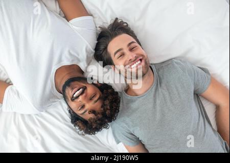 Glücklich Gay paar posiert für die Kamera im Bett Stockfoto