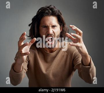 Du machest mein Blut zum Kochen. Studioaufnahme eines jungen Mannes, der vor Wut vor grauem Hintergrund schreit. Stockfoto