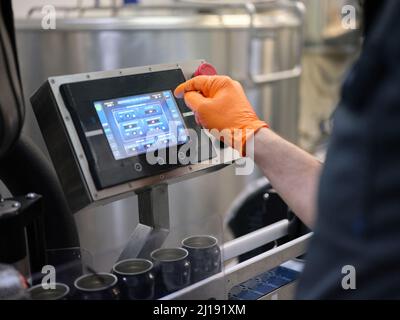 Arbeiter, der eine elektronische Bierabfüllmaschine in einer Brauerei betreibt Stockfoto