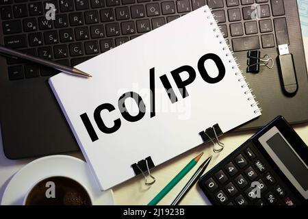 Ein Notebook mit Geschäft Anmerkungen erste Münze mit ICO vs IPO Initial Public Offering mit Office Tools auf Gelb blauen Hintergrund. Konzept der ch Stockfoto
