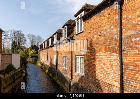 Historische Cottages aus roten Backsteinen mit Dachfenstern und gefüllten Fenstern, die auf den Fluss Dun in Hungerford, einer Stadt in der englischen Grafschaft Bekshire, blicken Stockfoto