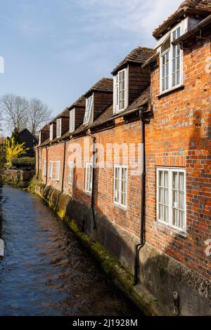 Historische Cottages aus roten Backsteinen mit Dachfenstern und gefüllten Fenstern, die auf den Fluss Dun in Hungerford, einer Stadt in der englischen Grafschaft Bekshire, blicken Stockfoto