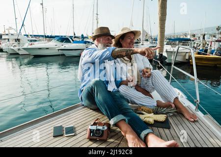 Ältere Paare trinken Champagner auf dem Segelboot während der Sommerferien - Fokus auf Gesichter Stockfoto