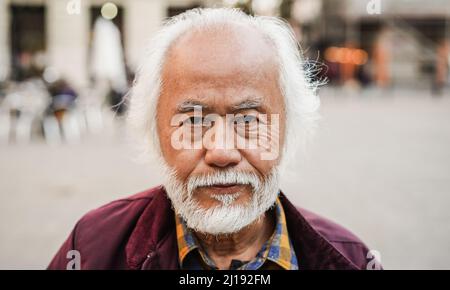 Asiatischer älterer Mann beim Blick auf die Kamera im Freien - Fokus auf Gesicht Stockfoto