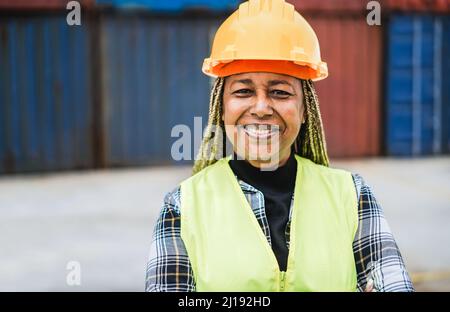 Arbeiter afrikanische ältere Frau lächelt vor der Kamera mit Industriehafen auf dem Hintergrund - Fokus auf Gesicht Stockfoto