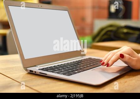 Eine Nahaufnahme einer Frau, die in einem modernen Café einen Laptop mit Kopierplatz auf einem Holztisch benutzt Stockfoto
