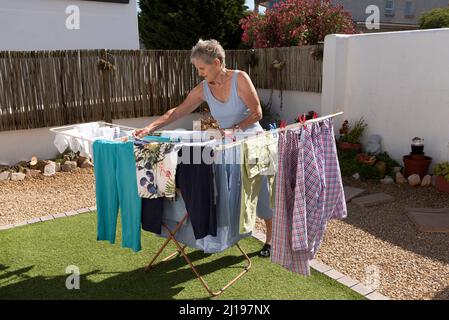 Südafrika. 2022. Ältere Frau, die an einem sonnigen Tag im Garten auswaschen und trocknen kann. Stockfoto