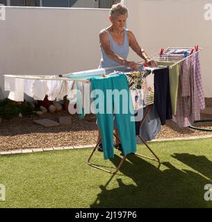 Südafrika. 2022. Ältere Frau, die an einem sonnigen Tag im Garten auswaschen und trocknen kann. Stockfoto