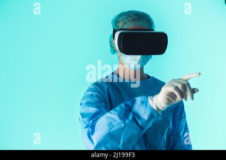 Kaukasischer Chirurg mit VR-Brille zur Vorbereitung auf die Operation. Überwachen der Patientensimulation. Mittellange Nahaufnahme mit blauem Hintergrund. Hochwertige Fotos Stockfoto