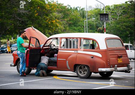 Männer reparieren ein altes kubanisches Auto an einer Straßenecke in Havanna, Kuba. Stockfoto