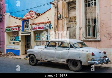 Geparktes Auto vor einem Gebäude in Havanna, Kuba, mit Fotos von kubanischen Revolutionshelden, darunter Fidel Castro. Stockfoto