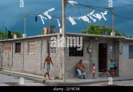 Bevor der Sturm einschlägt, genießen eine Familie und ihr Hund die Gesellschaft auf der ersten Stufe ihres Hauses in Manzanillo, Kuba. Stockfoto