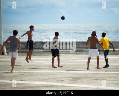 SJunge Jungen spielen Fußball auf einer Straße am Meer in Stockfoto