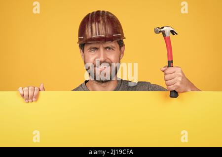 Arbeiterwerbung. Ankündigung. Glücklicher Arbeitstag. Lächelnder Mann im Helm mit Hammer. Stockfoto