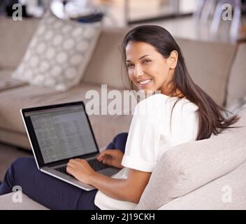 Machen Sie ein wenig gemächlich auf der Couch. Aufnahme einer attraktiven jungen Frau, die mit ihrem Laptop auf der Couch sitzt. Stockfoto